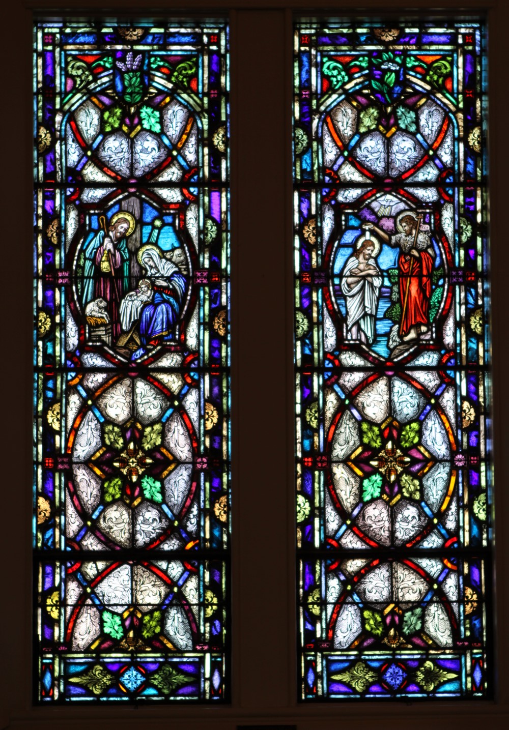 Two-panel stained glass window with Nativity and Baptism scenes